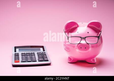 Piggybank Wearing Glasses And Calculator On Pink Background Stock Photo