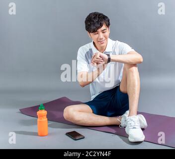 young man runner doing stretching exercise and checking smart watch Stock Photo