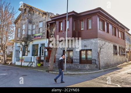 Istanbul, Turkey - February 13, 2020: Buyukada Island, one of the Princes Islands in Adalar region, a passerby walks past two two-story houses, one of Stock Photo
