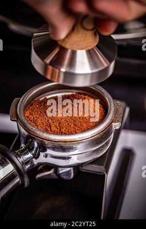 Barista presses ground coffee using tamper. Stock Photo