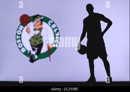 NEW YORK, USA, JUN 18, 2020: Boston Celtics logo of professional basketball club in american league. Silhouette of basket player in foreground. Sport Stock Photo