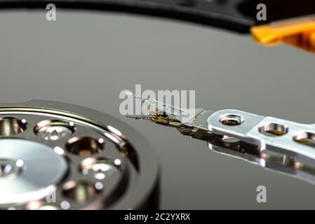 Macro shot of a magnetic needle on a hard disk platter, open HDD disk, perfectly clean surface. Stock Photo