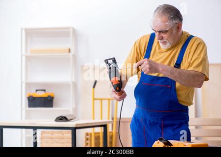 Old male carpenter working in workshop Stock Photo