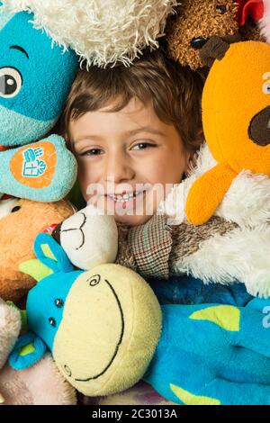 Creative portrait of a boy with his face surrounded by stuffed animals. Stock Photo