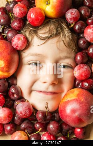 Creative portrait of a boy with his face surrounded by fruits. Stock Photo