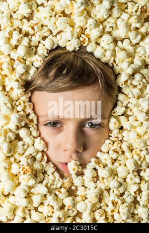 Creative portrait of a boy with his face surrounded by popcorn. Stock Photo