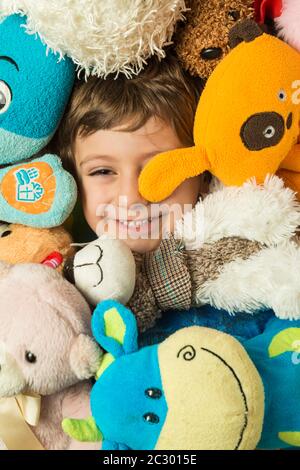 Creative portrait of a boy with his face surrounded by stuffed animals. Stock Photo