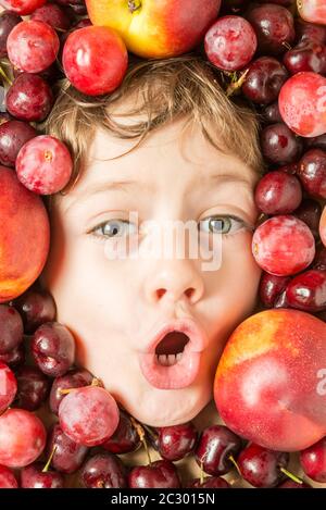 Creative portrait of a boy with his face surrounded by fruits. Stock Photo