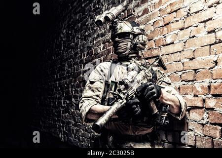 Special operations forces soldier, counter terrorism assault team fighter with night vision device on helmet and service rifle, low key indoor shot br Stock Photo