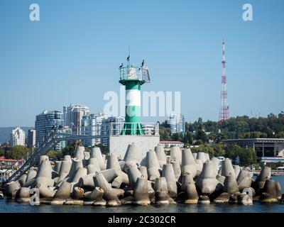 Green lighthouse with birds on a pier in the sea Stock Photo