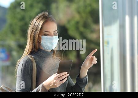 Commuter with a protective mask avoiding contagion checking bus schedule Stock Photo