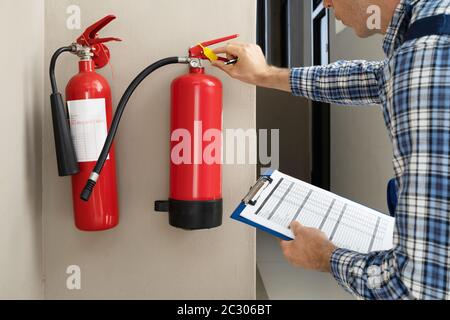 Male Professional Checking The Condition Of A Fire Extinguisher Stock Photo
