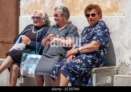 Three elderly Italian ladies rest of a stone seat in the famous holiday town of Ravello in Southern Italy Stock Photo