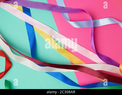 many silk multi-colored ribbons on a colored background, top view Stock Photo