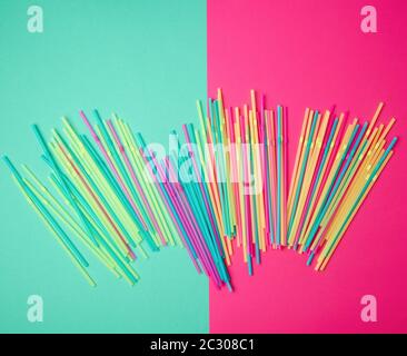 stack of multi-colored plastic tubes for a cocktail on a multi-colored background,  concept of environmental pollution by objects that decay in the gr Stock Photo