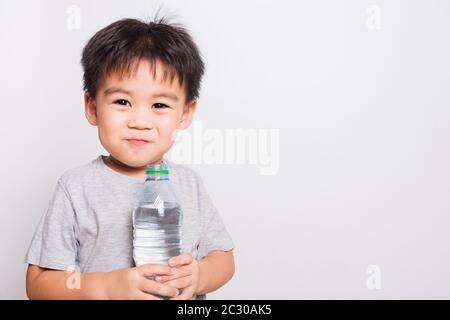 Closeup Asian face, Little children boy drinking water from Plastic bottle on white background with copy space, health medical care