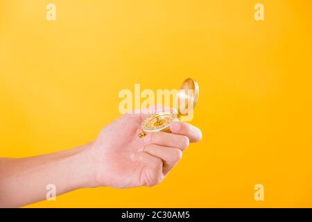 Hand holding antique brass compass isolated on yellow background with copy space for text Stock Photo