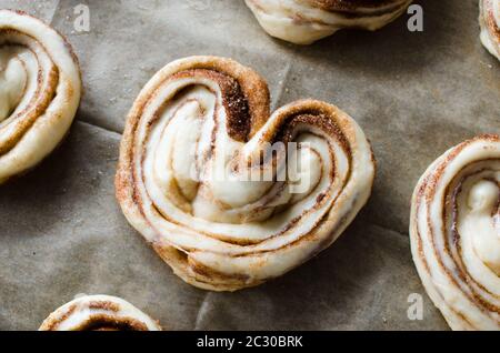 Raw unbaked buns. Ready to bake homemade traditional cinnamon buns on baking paper. Rustic style. Traditional pastry Stock Photo