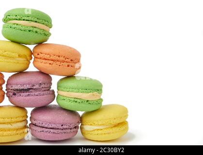 round baked multi-colored almond flour cakes macarons, dessert is laid in a stack in the shape of a triangle and isolated on a white background Stock Photo