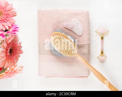 Massage brush, stone, face roller on pink towel Stock Photo