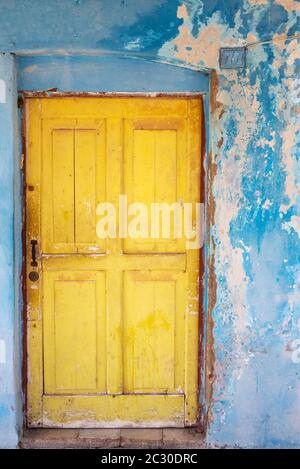 Colours, shapes and textures at the decayed facade of crumbling plaster and weathered wooden door, Gibara, Cuba Stock Photo