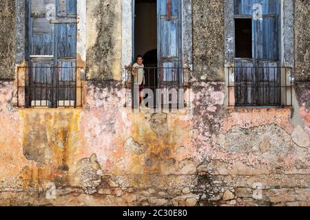 Colours, shapes and textures at the decayed facade of crumbling plaster and weathered wooden doors and windows, Gibara, Cuba Stock Photo