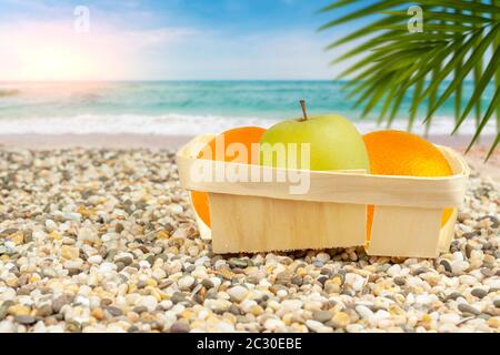 The apple in the package lies on a tropical beach. Stock Photo