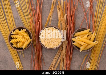 Mix of pasta made from wheat semolina, quinoa and azuki beans on a brown textured background Stock Photo