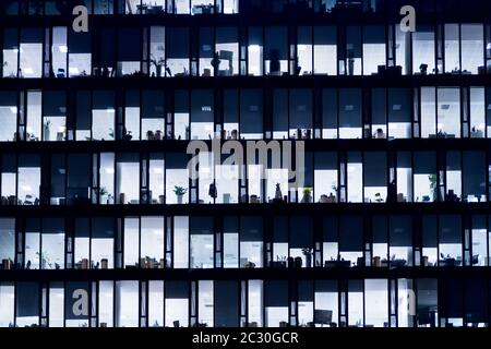 Office Building At Night. Late night at work. Glass curtain wall office building. Office building exterior in the late evening w Stock Photo