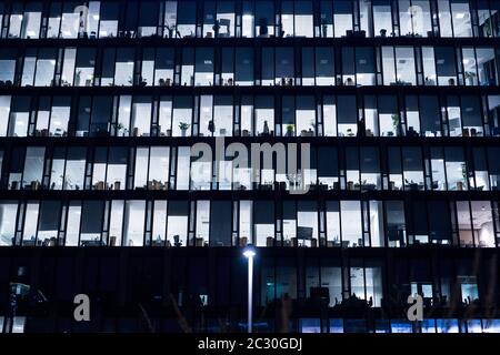 Office Building At Night. Late night at work. Glass curtain wall office building. Office building exterior in the late evening w Stock Photo