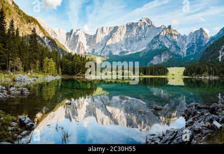 Scenic view of famous Superior Fusine Lake (Laghi di Fusine) with Mount Mangart in the background in golden morning light at sunrise, Tarvis, Italy Stock Photo