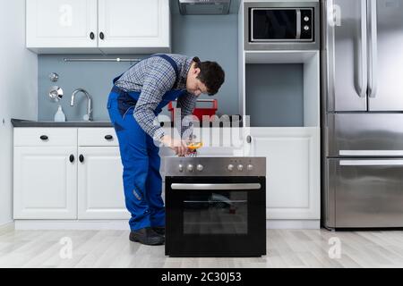 Young Male Technician Checking Oven With Digital Multimeter Stock Photo