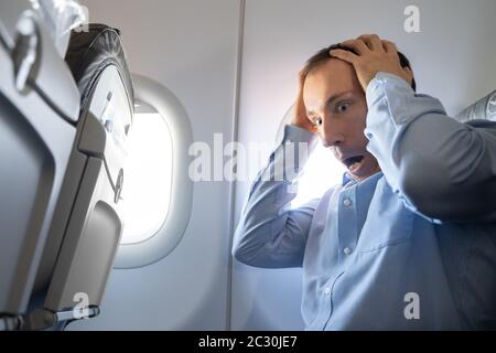 Young Man Having Anxiety Attack In Airplane Stock Photo