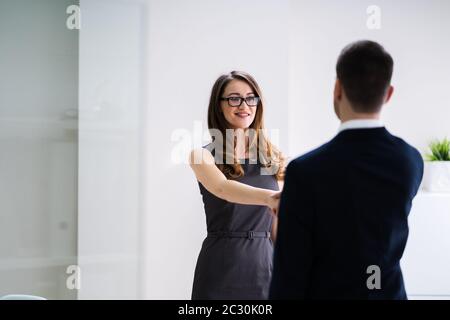 Smiling Young Businesswoman Shaking Hands With Her Partner In Office Stock Photo