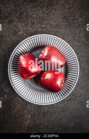 Three ripe red apples on plate. Top view. Stock Photo