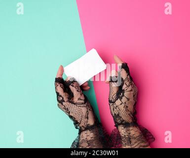 two female hands holding a stack of empty white paper business cards on a colored background, top view Stock Photo