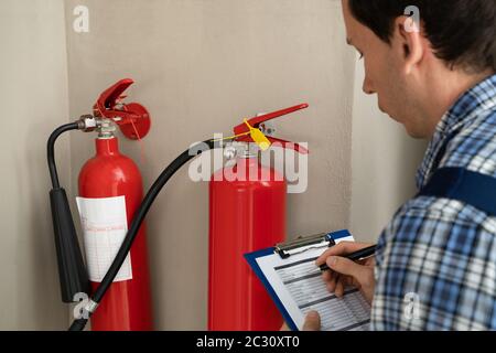 Male Professional Checking The Condition Of A Fire Extinguisher Stock Photo