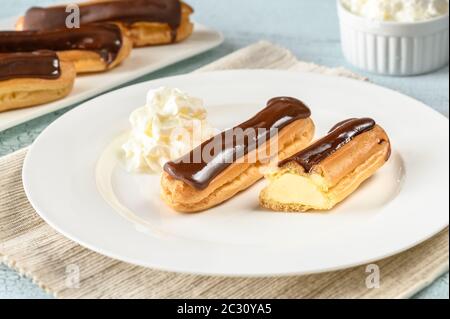 Eclairs with chocolate topping on serving plate Stock Photo