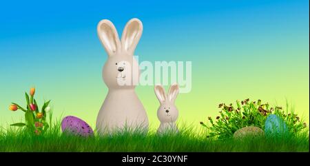 two easter bunnys stand on a meadow with easter eggs and flowes Stock Photo
