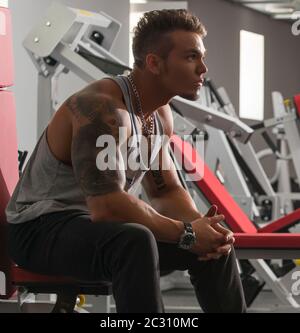 Handsome tattooed bodybuilder posing in gym Stock Photo
