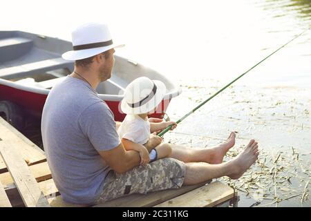 Father with little son fishing on the shore of the river Stock Photo