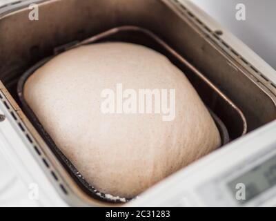 Tasty sliced loaf and bread machine on table Stock Photo