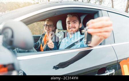 Student of driving school having passed his final test showing the car keys out of window Stock Photo
