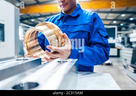 Apprentice in metalworking looking at workpiece being satisfied Stock Photo