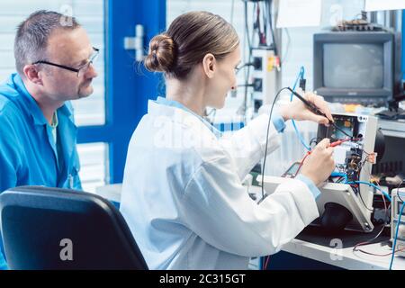 Team of electronic engineers testing a product prototype on test bench in the lab Stock Photo