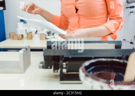 Experienced worker checking design or a print to be run on printing machine Stock Photo