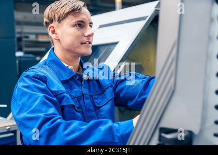 Young male worker programming lathe machine in factory Stock Photo
