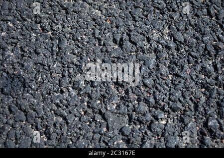 Grained  asphalt. Stone hard road surface. Old technology of road construction, macro photography. Stock Photo