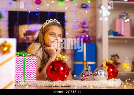 Beautiful ten-year-old girl lies on a rug in the New Year's interior and looks at the frame cheerfully Stock Photo