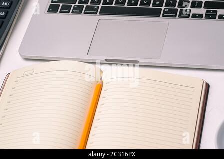 Computer keyboard and an open diary with a pencil. Empty page for text. Work at home or in the office Stock Photo